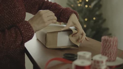 Woman Wrapping Christmas Gift at Home