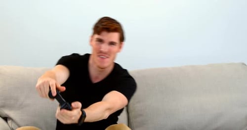 Man Playing Video Game Excitingly on Couch