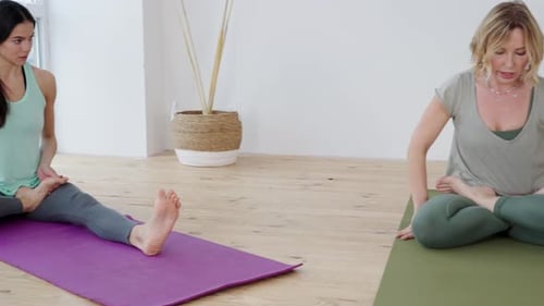 Junge Frau in Lotusposition praktiziert Yoga mit Trainer