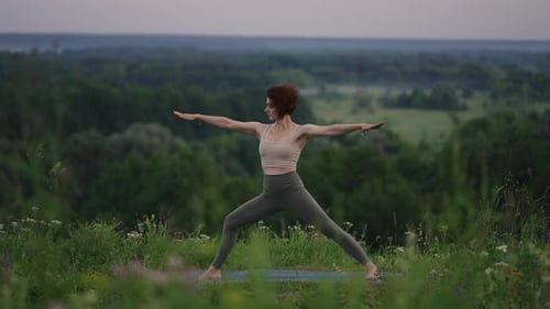 Woman Practicing Yoga Outdoors on Grassy Hilltop