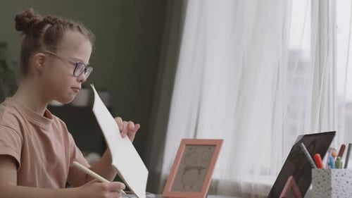 Young Girl Writing in Notebook at Desk