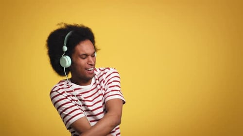 African man listening to music and dances in studio shot. Shot with RED helium camera in 8K.
