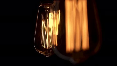 Close Up Retro Vintage Old Bulbs or Lamps Swing on Black Background. Edison Lamp Macro Footage Three