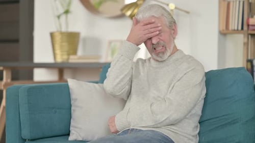 Stressed Old Man with Headache on Sofa
