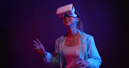 Young Asian woman playing metaverse virtual reality digital technology game with VR goggle.