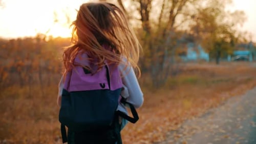 Kleines Mädchen mit Rucksack rennt zur Schule. Schul- und Kindergartenbildungskonzept. Ansicht von hinten