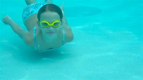 The Little Girl in the Swimming Pool Underwater and Smiling