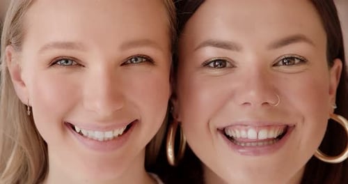 Two portrait faces of women mixed raced are looking close up at the camera and smiling