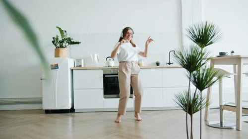 Woman Dancing and Singing in Kitchen with Headphones