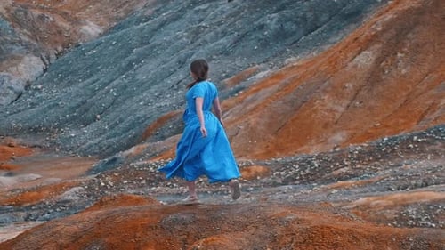 Woman Walking in Blue Dress on Hill