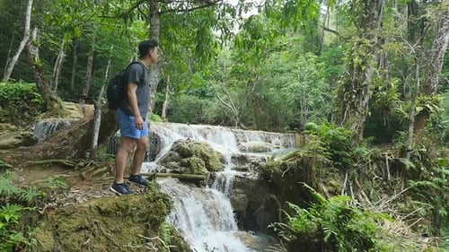 Man Hiking by Tropical Jungle Waterfall