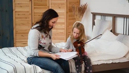Girl Learning Violin with Instructor on Bed
