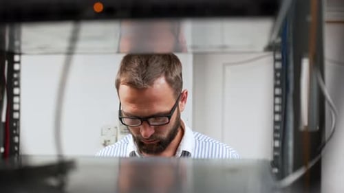 IT Technician Working on Network Cables in Server Rack