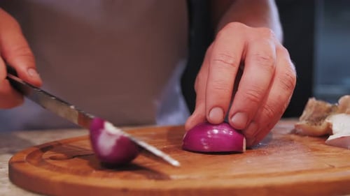 Chef Slicing Fresh Red Onion on Cutting Board