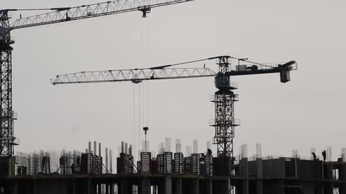 Silhouettes of Working Cranes During the Construction of a Highrise Building