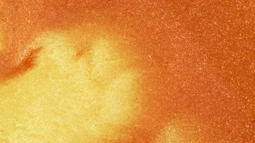Bunter goldener Sand bewegt sich organisch in bunter Flüssigkeit im Makro