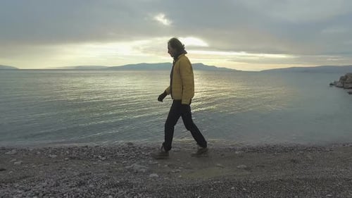 Mann spaziert im Winter bei Sonnenuntergang am Strand entlang