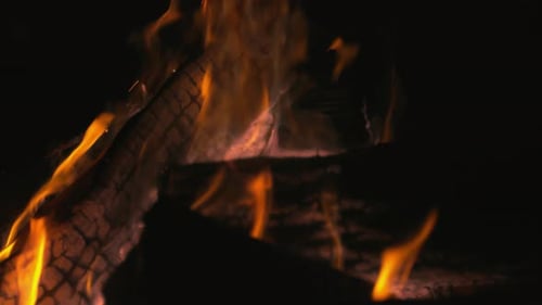 Nachts brennende Baumstämme in der Feuerstelle draußen. Zeitlupe. Unbearbeitete Version enthalten.