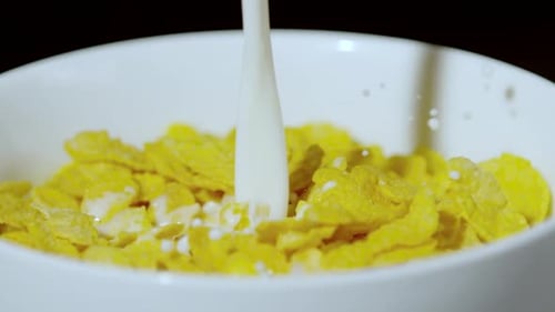 Milk Poured onto Yellow Corn Flakes in Bowl