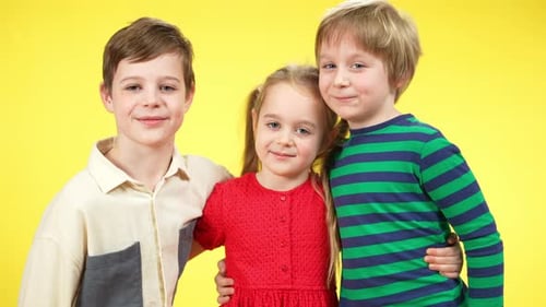 Smiling Children Embracing on Yellow Background