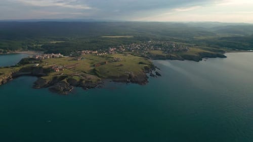 Drone flight around a picturesque rocky coastline with small resort village