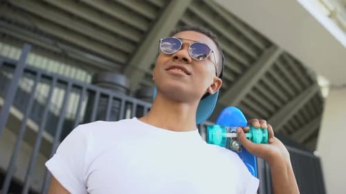 Smiling Young Adult with Skateboard Poses Outdoors