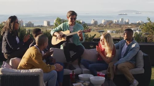 Friends Enjoy Guitar Music on Sunny Rooftop