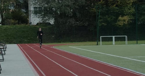 Motivated Disabled Man with Prosthetic Blade Running at Sports Field