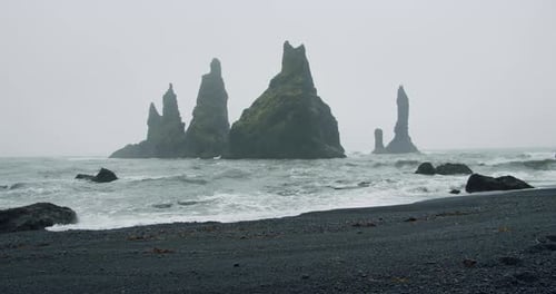 The Black Sand Beach of Reynisfjara with Waves Hitting the Shore on Foggy Rainy Stormy Day