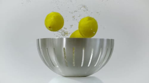 Lemons Splashing into Colander of Water