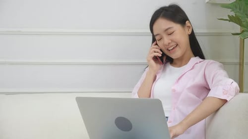 Smiling Woman Using Laptop and Talking on Phone