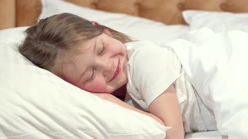 Linda niña va a dormir en su cama, madre metiendo la manta