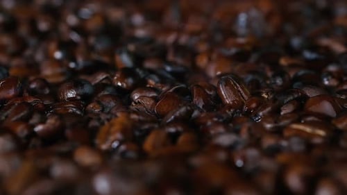 Nahaufnahme: Dunkle Kaffeebohnen werden geröstet. Frisch gerösteter aromatischer Kaffee, Kaffeebohnen