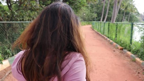 Woman Walks Along Tropical Lakeside Path