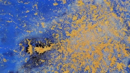 Gold Dust Swirling in Blue Liquid Abstract Background