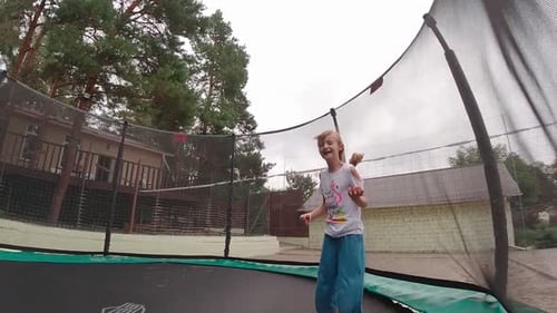 Happy Girl Jumping on Trampoline in Backyard