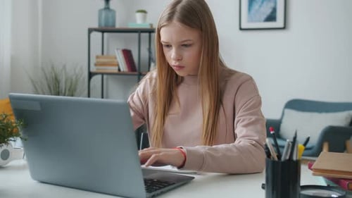 Teen Student Works at Laptop Computer Taking Notes