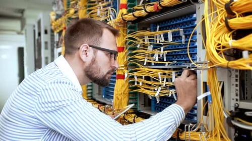 Man Adjusting Wires in a Server Room