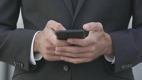 Male Hands Holding Black Smartphone and Typing on Screen