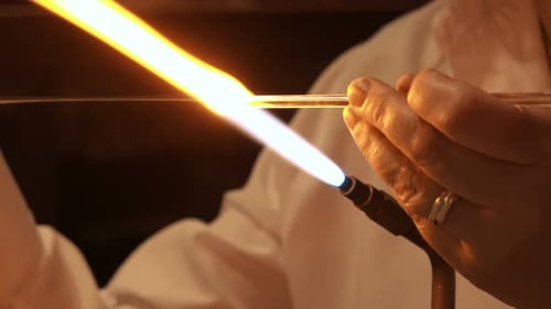 Ein Glasbläser, der in einer Glasbläserei aus geschmolzenem Glas handgefertigt