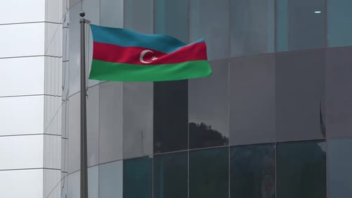 Azerbaijan Flag Waving on Flagpole in Front of Modern Building