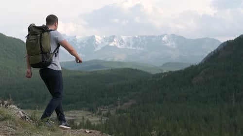 Successful Male Tourist on the Peak of the Mountain Raises His Hands Up