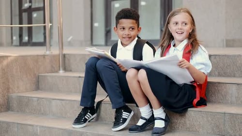 Schulkinder lesen Buch, während sie auf der Treppe sitzen
