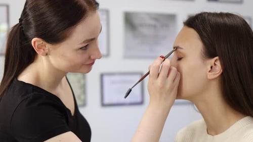 Makeup Artist Applying Makeup to Woman's Eyebrows