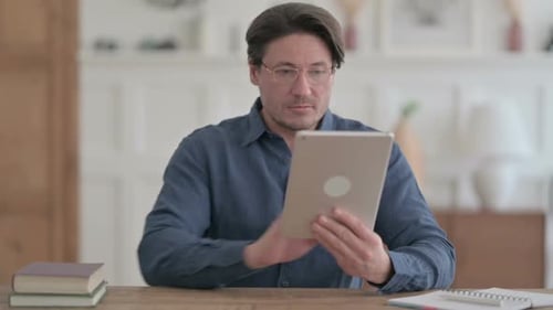 Young Man using Tablet while Sitting in Office