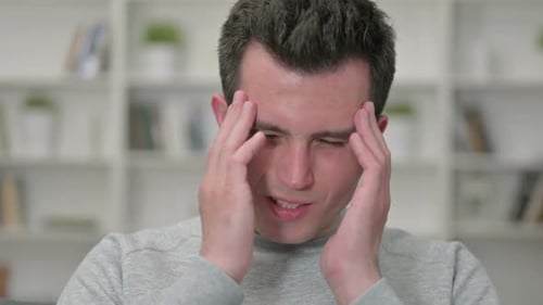 Young Adult Man Rubs Forehead in Close Up