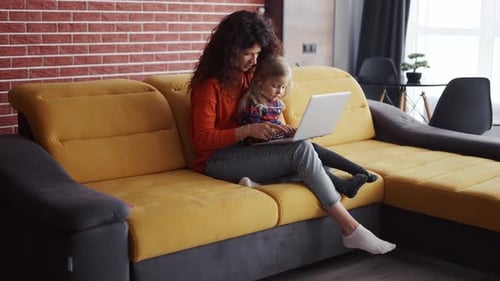 Mother and Child Use Laptop Together on Couch