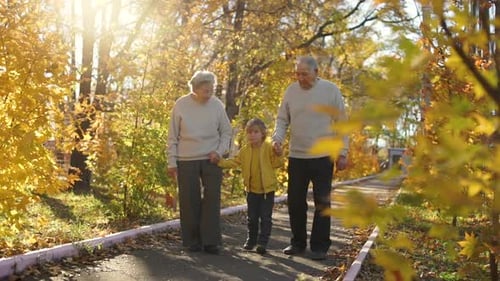 Grandparents and Child Walking in Autumn Park