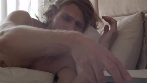 Man Wakes Up and Looks at Phone in Bed