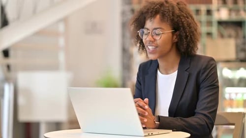 Happy African Businesswoman Doing Video Call on Laptop at Cafe